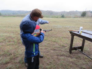 Isac showing a young man how to fire muzzleloader